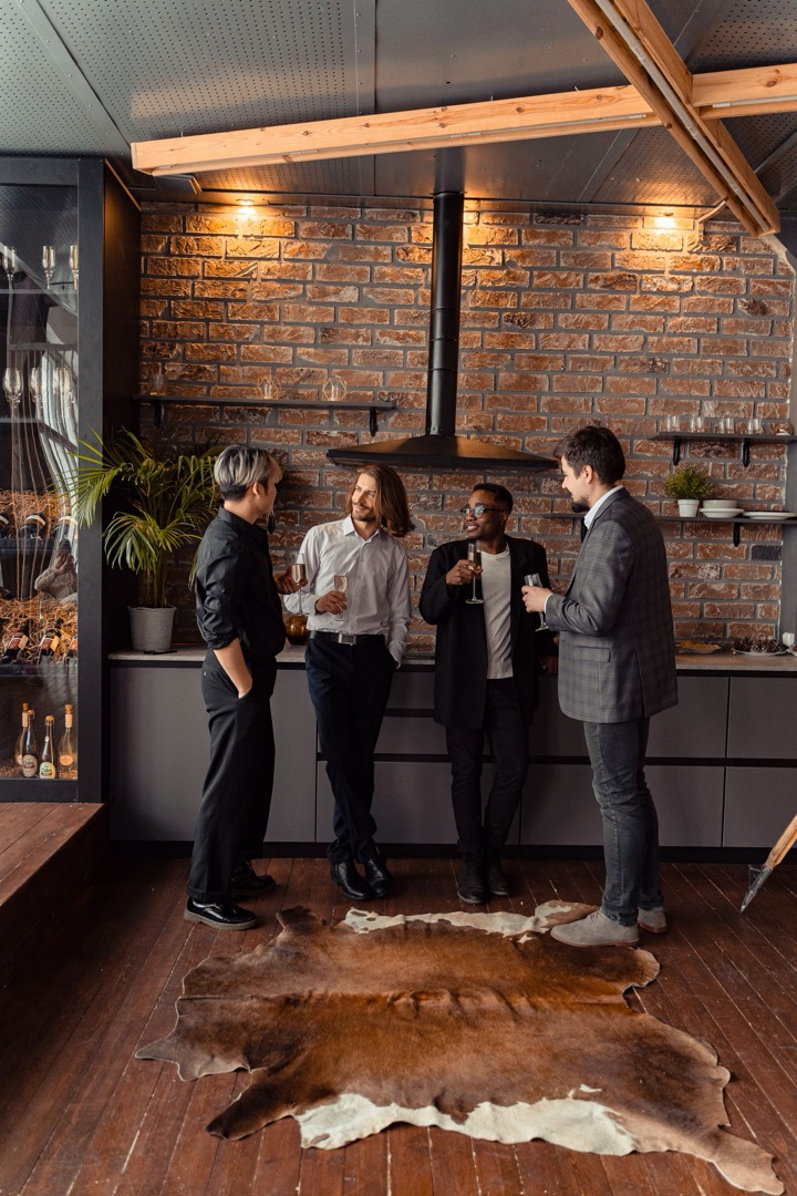 Four diverse adults enjoy a casual meeting in a stylish indoor lounge with brick walls.
