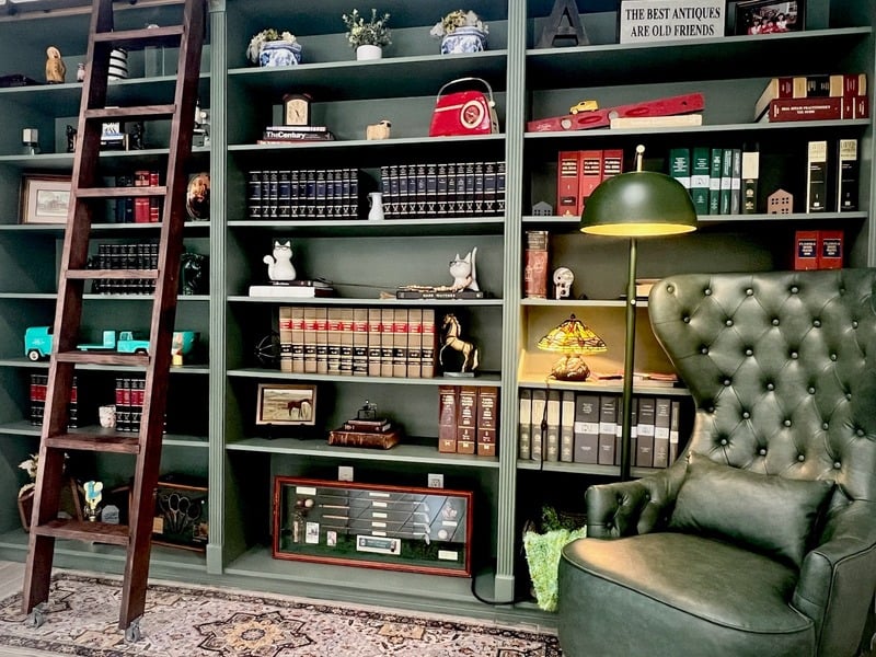 A cozy library space with brown leather chairs and wooden bookshelves filled with books.